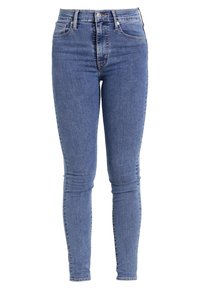 Jeans ajustados de denim azul claro, con una cintura alta, bolsillos delanteros y una textura suave con detalles de desvanecimiento sutil.