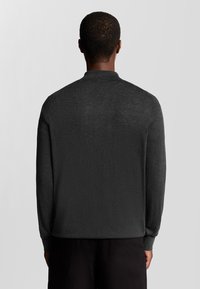 Donkergrijze gebreide trui met een hoge kraag en lange mouwen. Zachte textuur, slim fit en minimalistisch ontwerp zonder patronen of accenten.