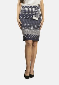 Falda azul marino con lunares beig, de forma ajustada, abertura en la parte trasera y detalle de lazo de tela en la cintura.