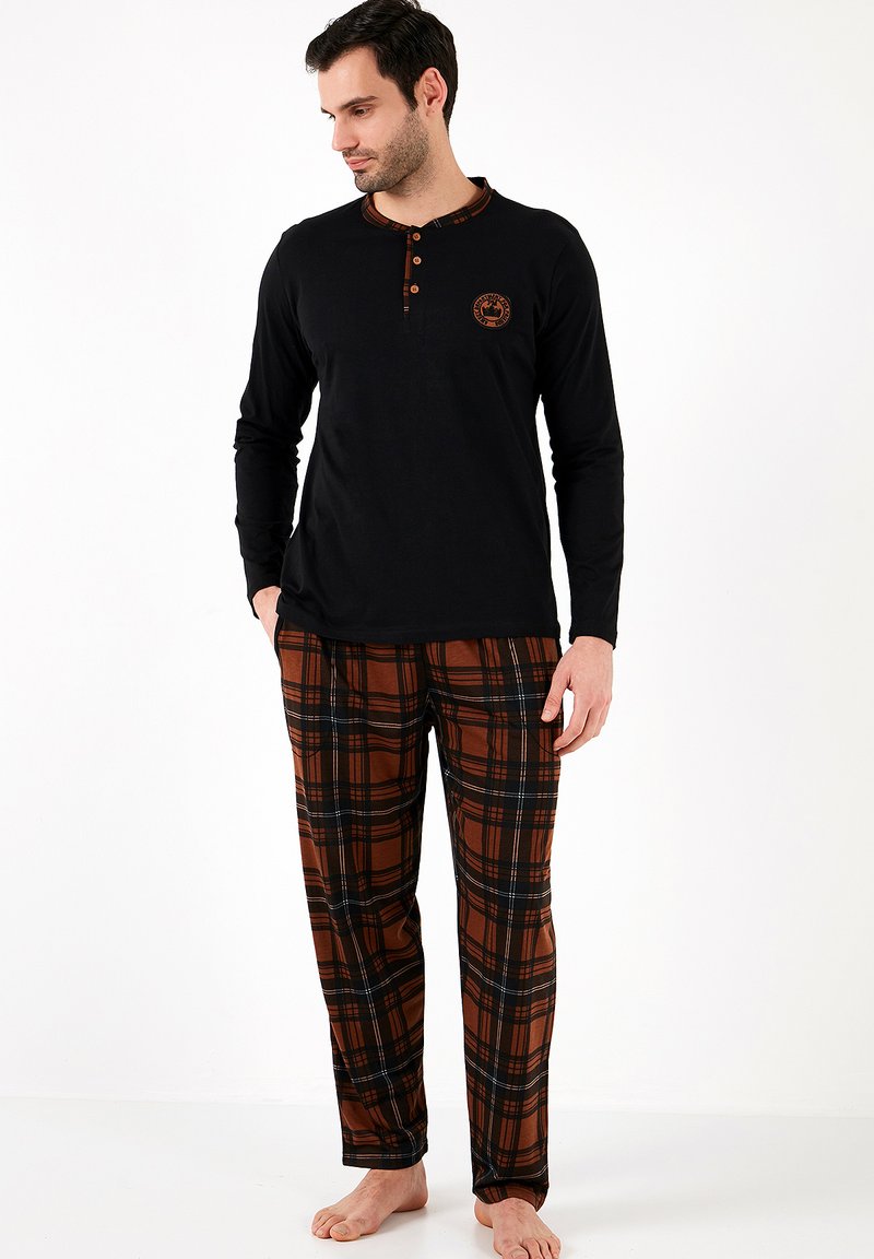Camisa negra de manga larga con tapeta de botones y acentos de cuadros; pantalones de cuadros marrones con líneas negras, hechos de una tela suave.