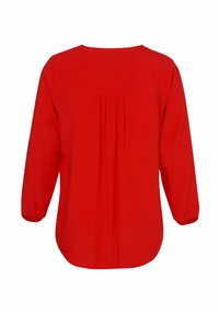 Helle rote Bluse mit langen Ärmeln und gerafften Falten unter dem Schulterbereich auf der Rückseite sowie elastischen Bündchen.