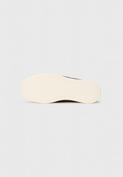 Shoe sole with smooth, light beige rubber outsole, rounded toe, and slight heel against a plain white background.