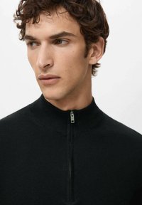 Musta vetoketjullinen pusero korkealla kauluksella, valmistettu teksturoidusta neuloksesta. Siinä on kapea vetoketju ja sileä viimeistely.