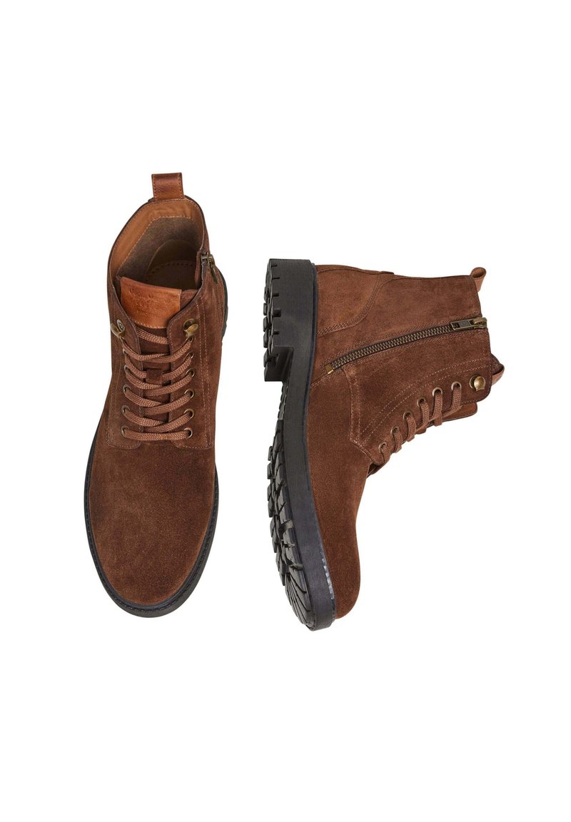 Botas de tobillo de ante marrón con cordones, cremallera lateral, suela de goma y agarre texturizado. Presenta ojales de metal y un asas en la parte posterior para facilitar su colocación.