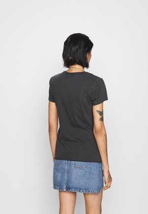 Černé tričko s krátkými rukávy a kulatým výstřihem, doplněné džínovou sukní. Měkká látka, klasický střih, minimalistický design, žádné viditelné logo.