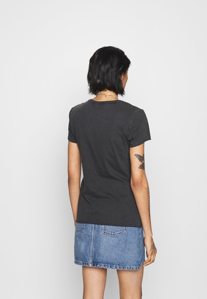 T-shirt noir à manches courtes avec un col rond, associé à une jupe en denim. Tissu doux, coupe classique, design minimaliste, sans logos visibles.
