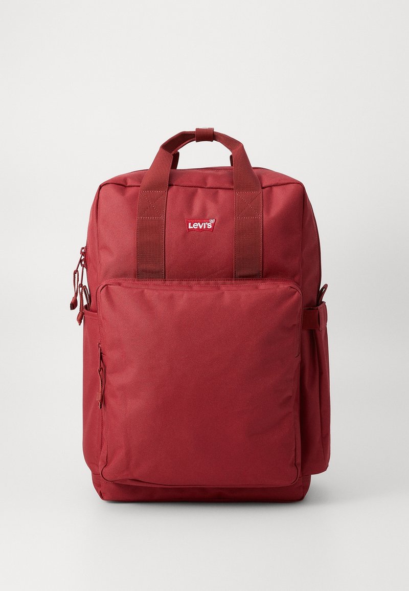 Sac à dos rouge Levi's avec poignées supérieures, poche avant zippée et poches latérales, montré sur un fond uni.