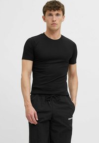 Schwarzes, kurzes, figurbetontes T-Shirt aus glattem, elastischem Material, kombiniert mit schwarzen Jogginghosen mit Kordelzug und Logo-Detail.
