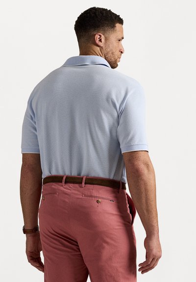 Tricou polo de culoare albastru deschis, cu un material texturat, având guler și mâneci scurte, asortat cu pantaloni roz și o curea maro.