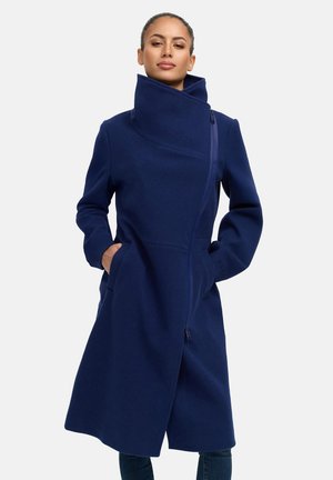 Navy blue coat with a high collar, side pockets, and an asymmetrical zipper. Made from a textured fabric with a tailored fit.