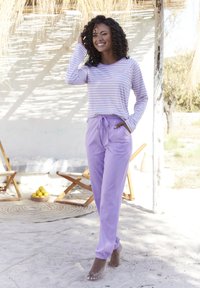 Chemise rayée à manches longues en lavande et blanc avec une coupe décontractée, accompagnée d'un pantalon de jogging violet clair avec une taille élastique et des poignets.