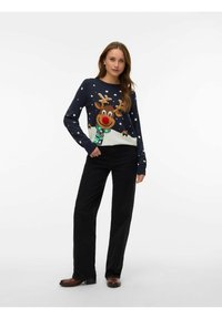 Granatowy sweter z wzorem renifera, kropkami i zimowym pejza�żem; zestawiony z czarnymi spodniami i brązowymi butami. Miękka dzianina.