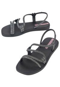 Sandali neri con cinturini glitterati caratterizzati da un design intrecciato. La suola è piatta e textured per una migliore aderenza. Costruzione leggera e flessibile.