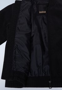 Čierna bomber bunda s hladkou vnútornou podšívkou. Obsahuje zips, elastický pás a manžety a na vnútornej strane je nášivka s logom.