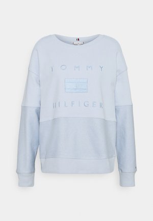 Light blue Tommy Hilfiger sweatshirt with textured lower sleeves and torso, featuring raised brand name and logo on the chest.