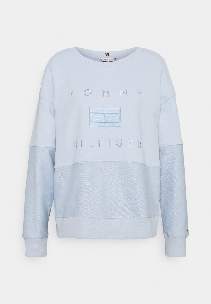 Sweatshirt Tommy Hilfiger bleu clair avec manches inférieures et torse texturés, arborant le nom de la marque en relief et le logo sur la poitrine.