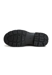 Zwarte schoenzool met een getextureerd rubber oppervlak, met diepe profielgroeven voor grip en uitgesproken noppen voor stabiliteit en tractie.