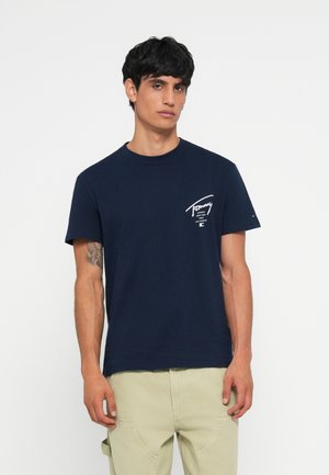 Marineblå bomulds T-shirt med korte ærmer, rund halsudskæring og hvid tekstlogo på venstre bryst. Glat tekstur, klassisk fit design.