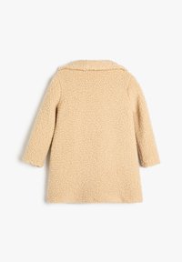 Abrigo beige borroso con un exterior texturizado y suave, mangas largas y un cuello clásico, que presenta un corte recto y sin cierres visibles.
