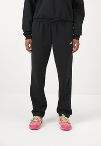 Μαύρες φόρμες με ελαστική μέση και κορδόνι, με λευκό λογότυπο στο αριστερό ισχίο και χαλαρή εφαρμογή. Ιδανικές για καθημερινή χρήση.