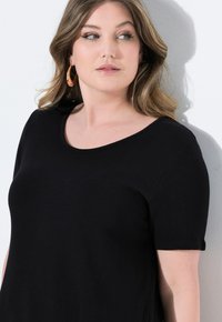 Maglietta nera a maniche corte realizzata in un tessuto liscio e morbido; presenta un colletto arrotondato e una vestibilità comoda.