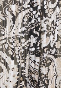 Tissu fluides dans des nuances de noir, blanc et beige avec des motifs floraux et paisley complexes. Le matériau présente un léger éclat et une texture.