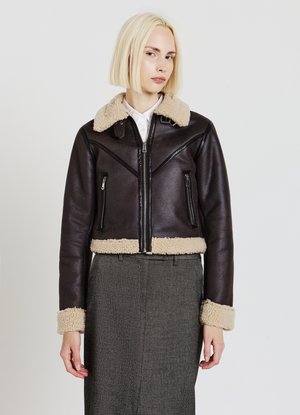 Veste bomber en cuir marron avec un col et des poignets en shearling de couleur claire, dotée de poches zippées et d'un design court.