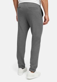 Grå joggebukser i strukturert stoff, med baklommer og ribbede hems, kombinert med hvite sneakers.