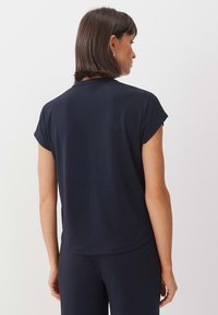 Navy blue short-sleeve top made of soft fabric, featuring a round neckline and a curved hem. Simple design with no visible patterns or embellishments.
