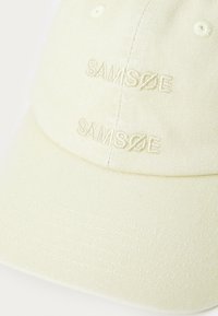 Yellow cap with embroidered "SAMSOE" branding. Made from textured fabric, featuring a curved brim and stitched detailing on the visor.