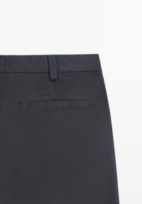 Svarta byxor med en slät textur, rak skärning, en skräddarsydd midjeresår och en enda bakficka. Söm-detaljer är synliga.