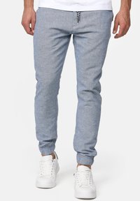 Helle blaue Jogginghose aus gewebtem Stoff. Mit elastischen Bündchen und einem Kordelzugbund. Kombiniert mit weißen Turnschuhen.