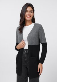 Gray and black color-block cardigan with long sleeves, open front, and two front pockets, made from soft knit material.