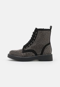 Black ankle boots with a textured fabric covered in silver studs, featuring a lace-up front, a pull tab, and a thick rubber sole.