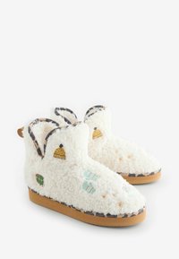 Karvased valged sussid, millel on mitmevärvilised tikitud mustrid (mütsid, kindad) ning beežast kummist tald leopardimustrilise äärisega.