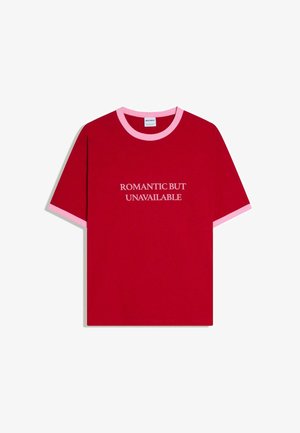 Piros rövid ujjú póló rózsaszín gallérral és ujjvégekkel, melynek elején fehér felirat: "ROMANTIKUS, DE ELÉRHETETLEN".