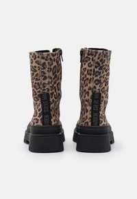 Ankelstøvler med leopardprint laget av teksturert materiale, svarte gummisåler og glidelåser på siden for enkel påkledning. Har svart merkevare på hælen.