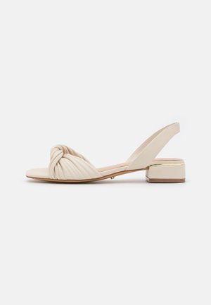 Sandales slingback beige avec un devant noué et plissé, petit talon carré, texture lisse et subtile accent en or au talon.