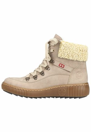 Bottes ankle en suède beige avec un large bord en fourrure crémeuse, lacets beiges et quincaillerie métallique. Présente une semelle en caoutchouc marron texturé.