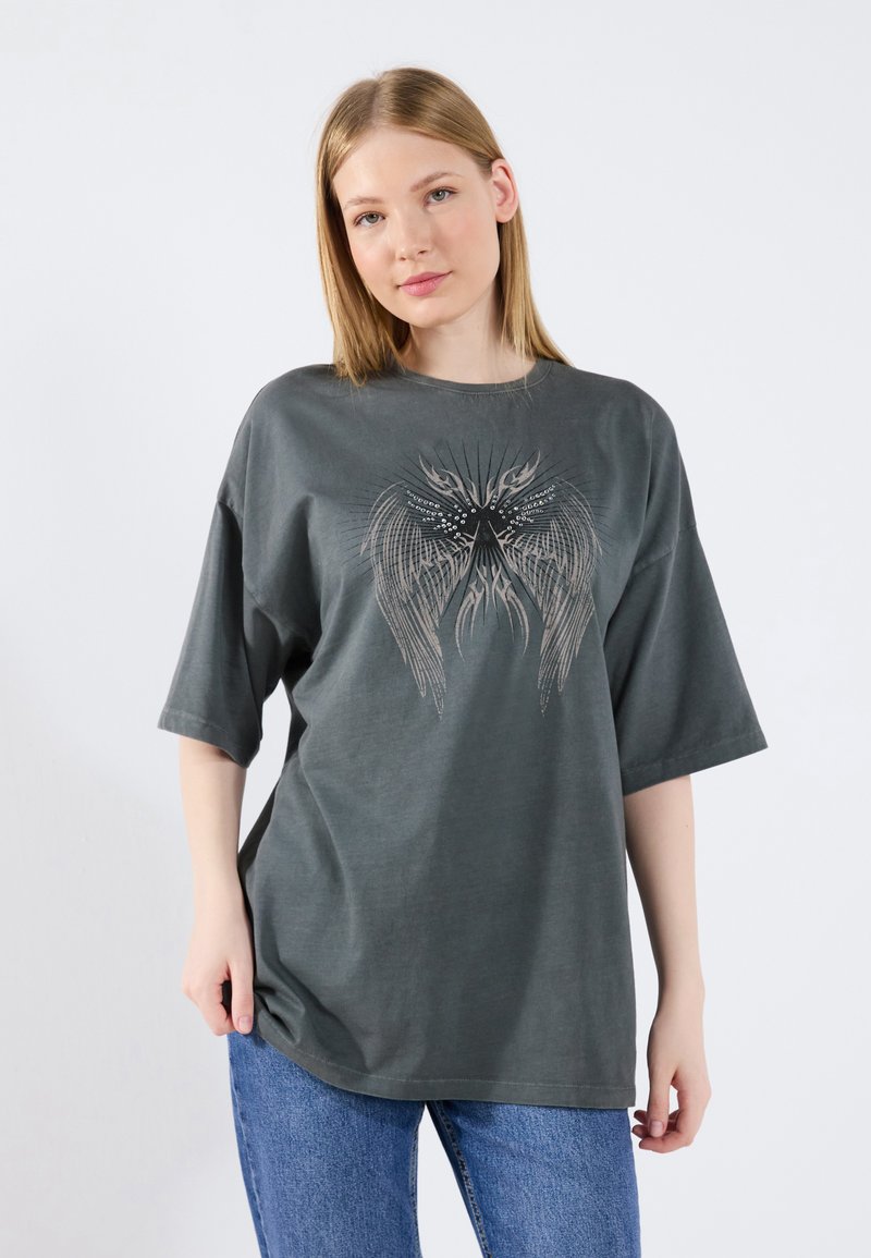 Gray oversized t-shirt with short sleeves, featuring a detailed wing graphic design in lighter shades. Made from soft cotton material.