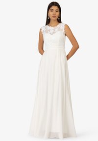 Weißes Kleid mit tailliertem Oberteil und Spitzenüberzug sowie einem fließenden Rock. Ärmelloses Design mit floralen Spitzelementen und einer sanften Textur.
