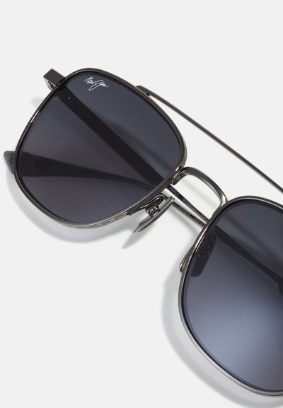 Black metal sunglasses with large dark lenses, thin arms, and a decorative pattern on the frame, featuring a subtle logo on one lens.