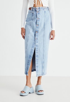 Light blue denim midi skirt with a front slit, button closure, and contrasting stitching. Paired with light blue slip-on platform shoes.