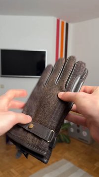 Barna gyapjú kesztyű bőrszegélyekkel és gombokkal, texturált felülettel és öt ujjjal. A kéz a kesztyűt tartja.