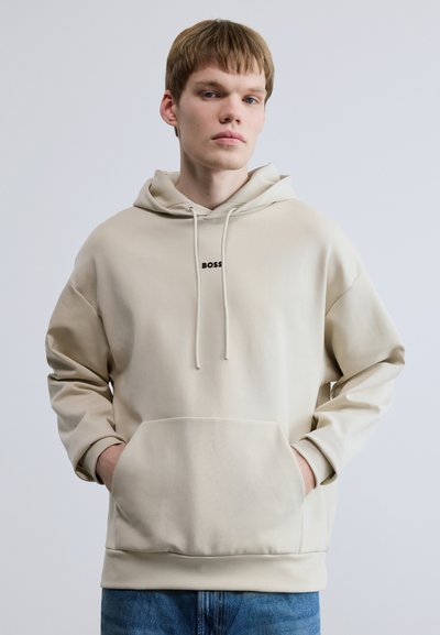 Sweat à capuche beige avec une poche avant et un cordon de serrage. Présente un petit logo noir "BOSS" sur la poitrine. Confectionné en tissu doux.