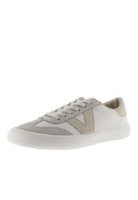 Des baskets en cuir blanc présentent un capuchon en daim gris, des accents beiges et un logo en V texturé sur le côté. Bout arrondi avec des lacets plats.