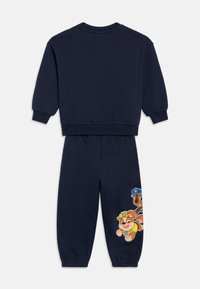 Marineblauw katoenen trainingspak met geribbelde manchetten en tailleband. Voorzien van kleurrijke cartoonfiguren op het linkerbeen van de broek.