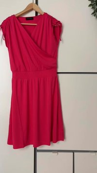 Rotes Wickelkleid mit kurzen Ärmeln, gerafften Schulterdetails, smockiertem Taillenbund und fließendem Rock. Hergestellt aus leichtem Stoff.