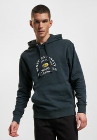 Dunkelgrüner Kapuzenpullover mit Kordelzug, Kängurutasche und weißem Textlogo. Verfügt über eine lockere Passform mit gerippten Bündchen und Saum.