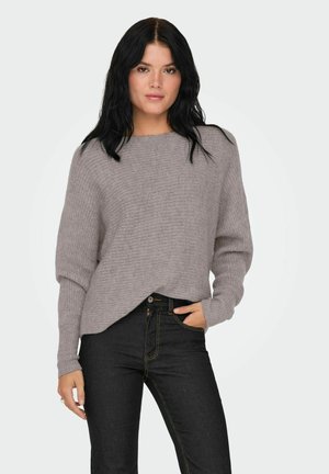 Lys grå, ribbet sweater med en afslappet pasform, rund halsudskæring og lange ærmer, parret med mørke jeans med gule stropper.